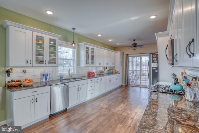 kitchen featuring wood finished floors, a ceiling fan, a sink, white cabinets, and appliances with stainless steel finishes