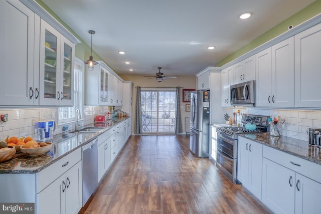 kitchen with white cabinets, appliances with stainless steel finishes, wood finished floors, and a sink