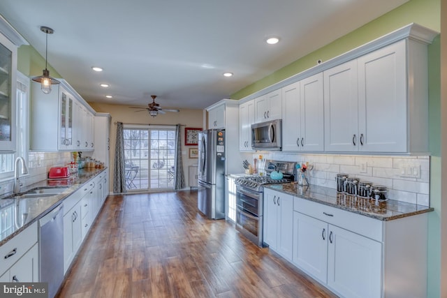 kitchen featuring a ceiling fan, a sink, glass insert cabinets, appliances with stainless steel finishes, and white cabinetry