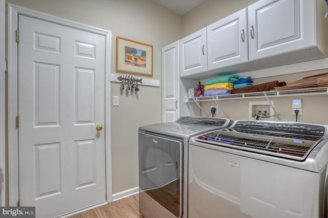 laundry area with separate washer and dryer, cabinet space, light wood-type flooring, and baseboards