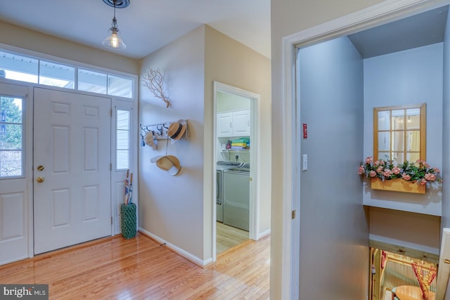 entryway featuring washer and dryer, light wood-style floors, and baseboards