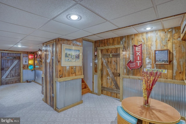 interior space with carpet flooring, wood walls, and a paneled ceiling