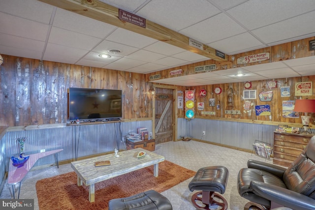 living area featuring wooden walls, a drop ceiling, and visible vents