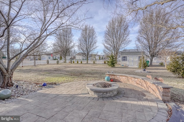 view of patio with an outbuilding, a fire pit, and fence