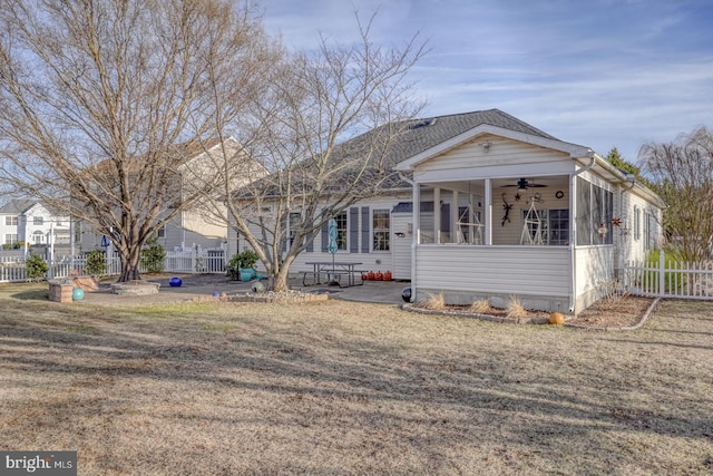 view of front facade with a front lawn, fence, a sunroom, a ceiling fan, and a patio