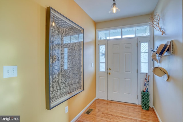 foyer with light wood-style flooring, baseboards, and visible vents