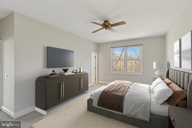 bedroom featuring light colored carpet, a ceiling fan, and baseboards