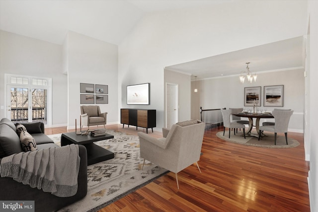 living area featuring a notable chandelier, high vaulted ceiling, crown molding, and wood finished floors