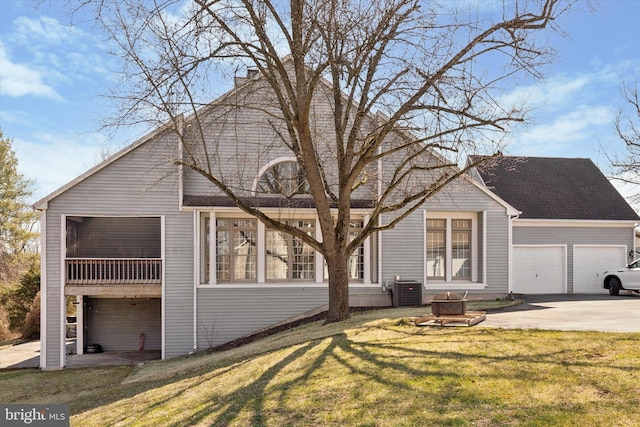 view of front of property featuring an outdoor fire pit, cooling unit, concrete driveway, a front yard, and a sunroom