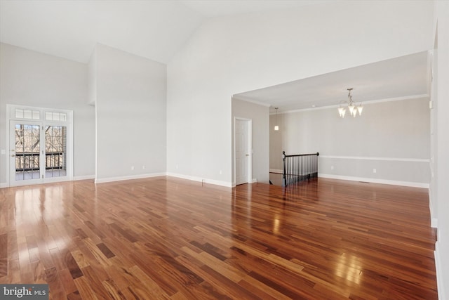 unfurnished living room featuring an inviting chandelier, wood finished floors, baseboards, and high vaulted ceiling