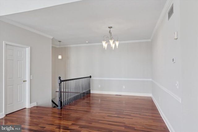 empty room with visible vents, wood finished floors, crown molding, baseboards, and a chandelier