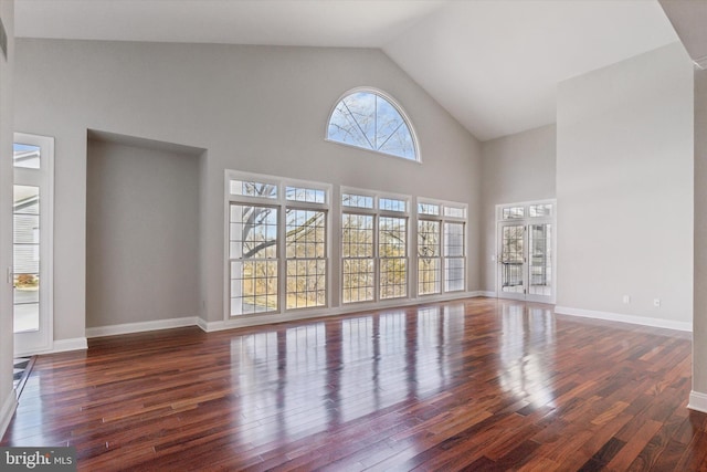 unfurnished living room featuring high vaulted ceiling, baseboards, and hardwood / wood-style floors