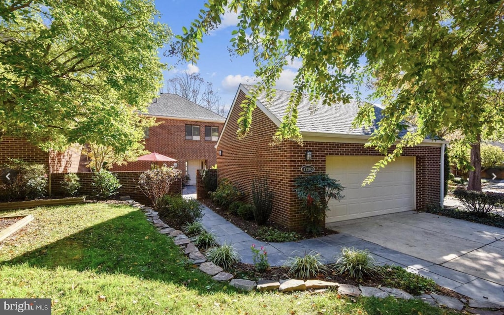 view of home's exterior with brick siding, roof with shingles, a lawn, a garage, and driveway