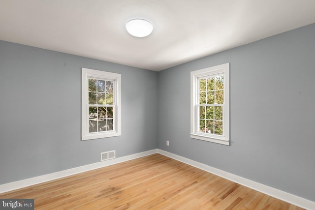 empty room featuring visible vents, baseboards, and light wood finished floors