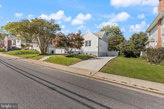 view of front facade featuring a residential view, stucco siding, driveway, and a front yard