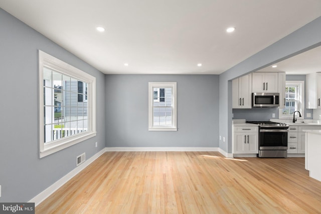 kitchen with visible vents, light countertops, appliances with stainless steel finishes, light wood-style floors, and a sink