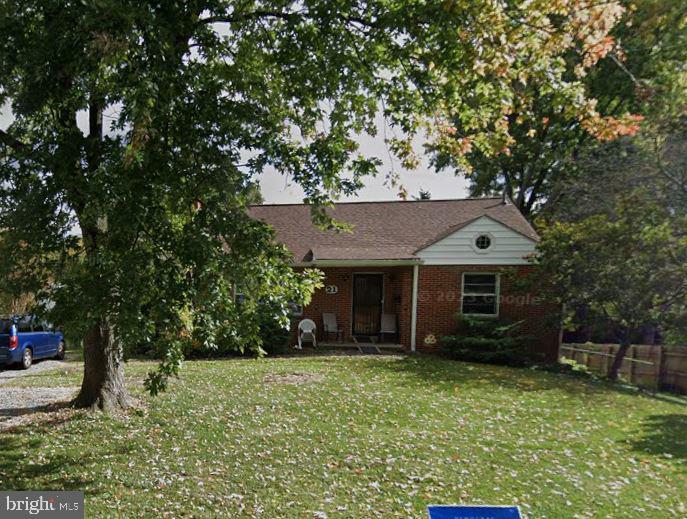 view of front of home with brick siding, a front lawn, and fence