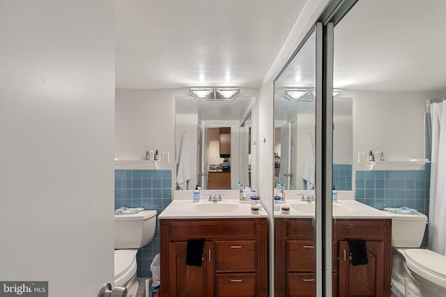 full bath featuring toilet, tile walls, wainscoting, and vanity