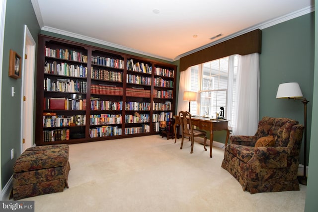 sitting room featuring visible vents, a baseboard heating unit, wall of books, carpet floors, and ornamental molding