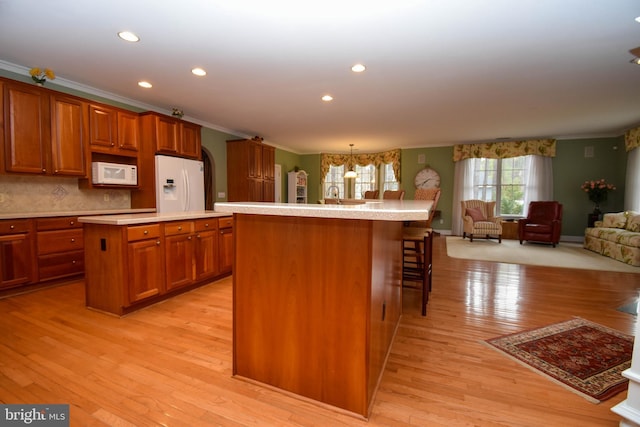 kitchen featuring white appliances, crown molding, brown cabinets, and a kitchen island