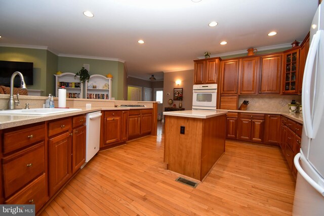 kitchen featuring white appliances, light wood finished floors, a sink, light countertops, and brown cabinets
