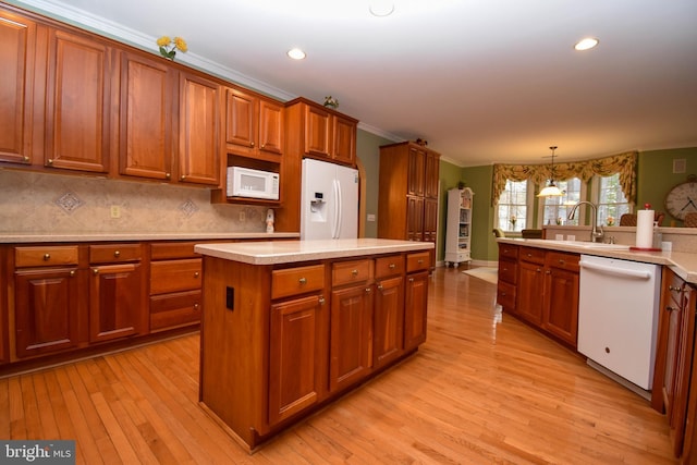 kitchen featuring light countertops, light wood-style flooring, brown cabinetry, white appliances, and a sink