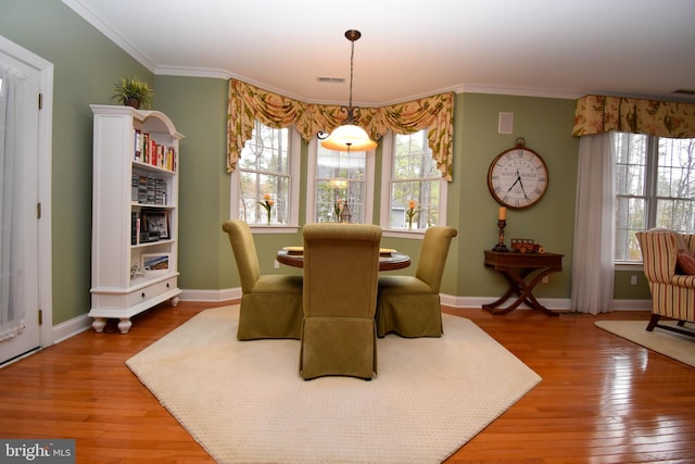 dining area featuring hardwood / wood-style floors, crown molding, and baseboards