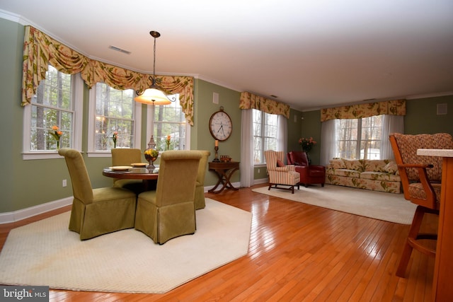 dining space with hardwood / wood-style floors, visible vents, baseboards, and ornamental molding