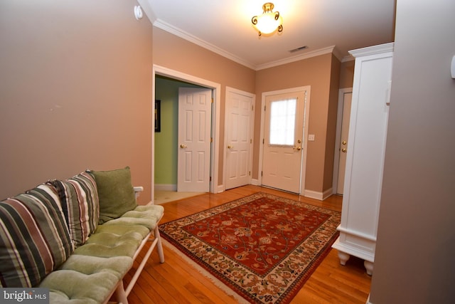 entrance foyer featuring visible vents, baseboards, wood finished floors, and ornamental molding