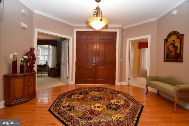 entryway with crown molding, light wood-style floors, and baseboards
