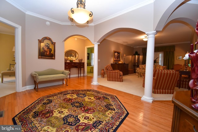 foyer with decorative columns, arched walkways, hardwood / wood-style floors, and crown molding
