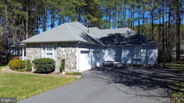 view of front of house with stone siding, driveway, an attached garage, and a shingled roof