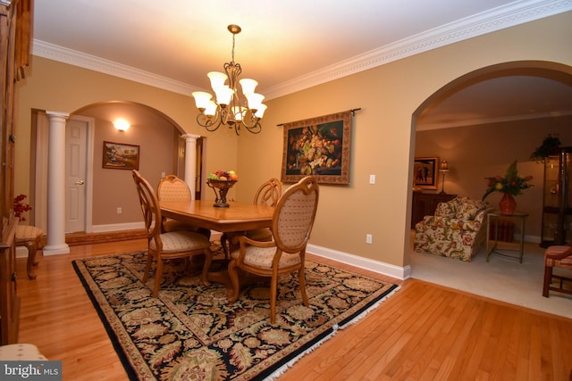dining space featuring arched walkways, light wood-type flooring, and decorative columns