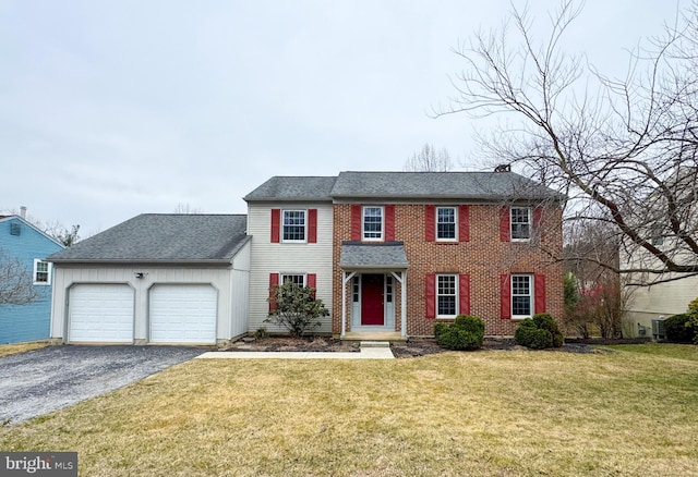 colonial home with aphalt driveway, a garage, roof with shingles, and a front yard