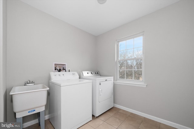 laundry room with a sink, light tile patterned flooring, baseboards, laundry area, and washing machine and clothes dryer