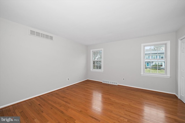 unfurnished room with visible vents, a healthy amount of sunlight, and hardwood / wood-style floors