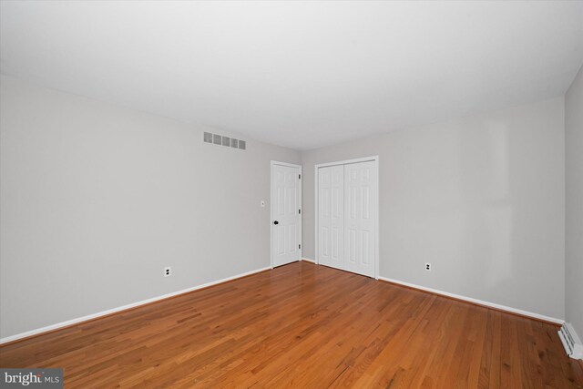 interior space featuring visible vents, baseboards, a closet, and wood finished floors