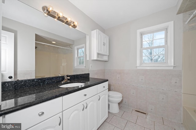 full bath featuring tile patterned flooring, visible vents, toilet, tile walls, and a shower