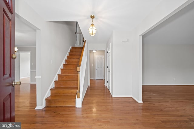 foyer featuring baseboards, wood finished floors, and stairs