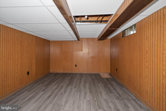 finished basement with wood walls, baseboards, and wood finished floors