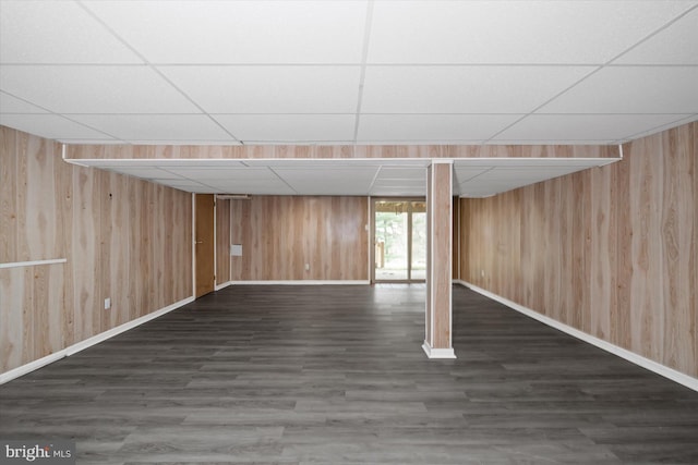 basement featuring wood finished floors, baseboards, wood walls, and a paneled ceiling