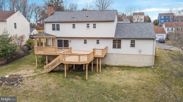 rear view of property with a yard, a wooden deck, a chimney, and a shingled roof