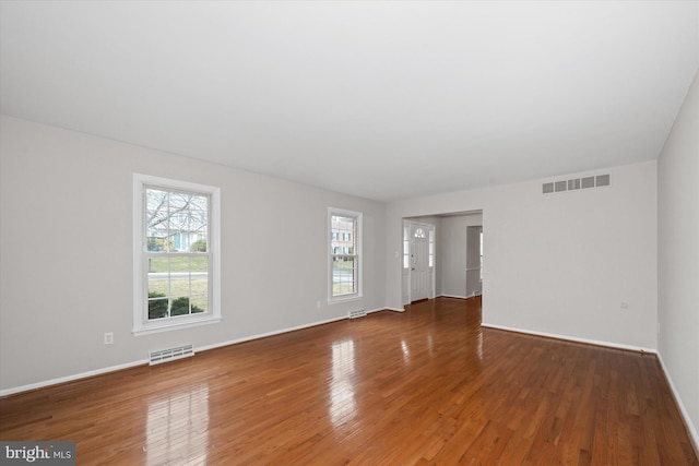 unfurnished room with visible vents, baseboards, and hardwood / wood-style flooring