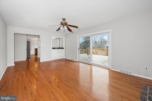 unfurnished living room featuring visible vents, wood-type flooring, baseboards, and a ceiling fan