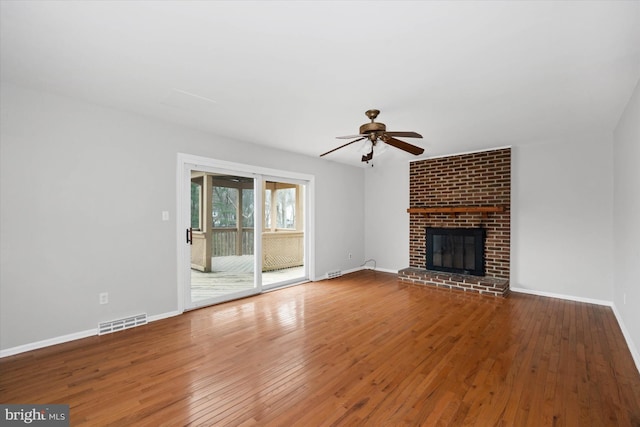 unfurnished living room featuring visible vents, a brick fireplace, baseboards, hardwood / wood-style floors, and a ceiling fan