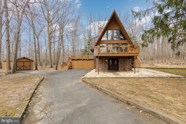 exterior space featuring brick siding, a wooden deck, stairs, and an outdoor structure