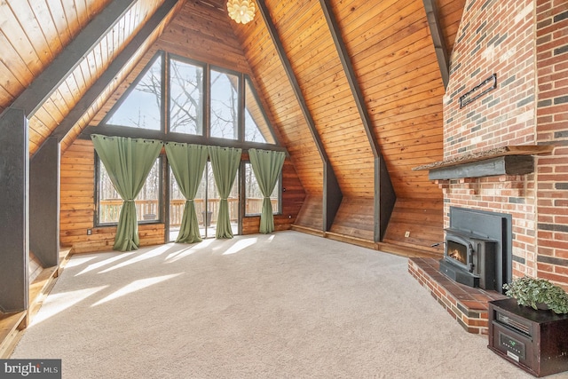 unfurnished living room featuring a wealth of natural light, a wood stove, wood ceiling, and wood walls