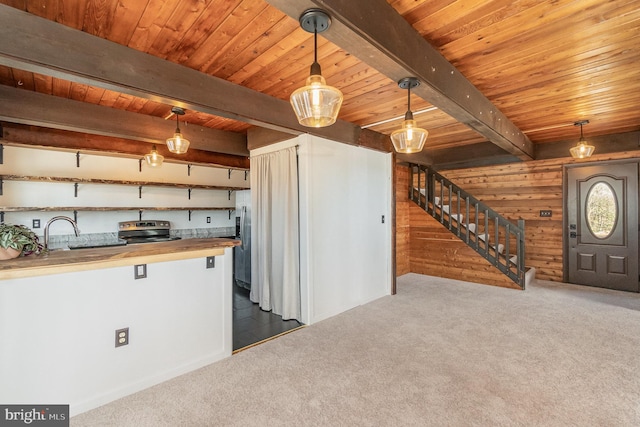 kitchen with beam ceiling, butcher block countertops, stainless steel appliances, carpet, and wooden ceiling