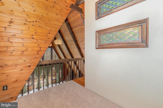 corridor with lofted ceiling with beams, carpet floors, wood ceiling, and an upstairs landing