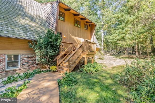 view of side of property with a deck, stairway, and brick siding